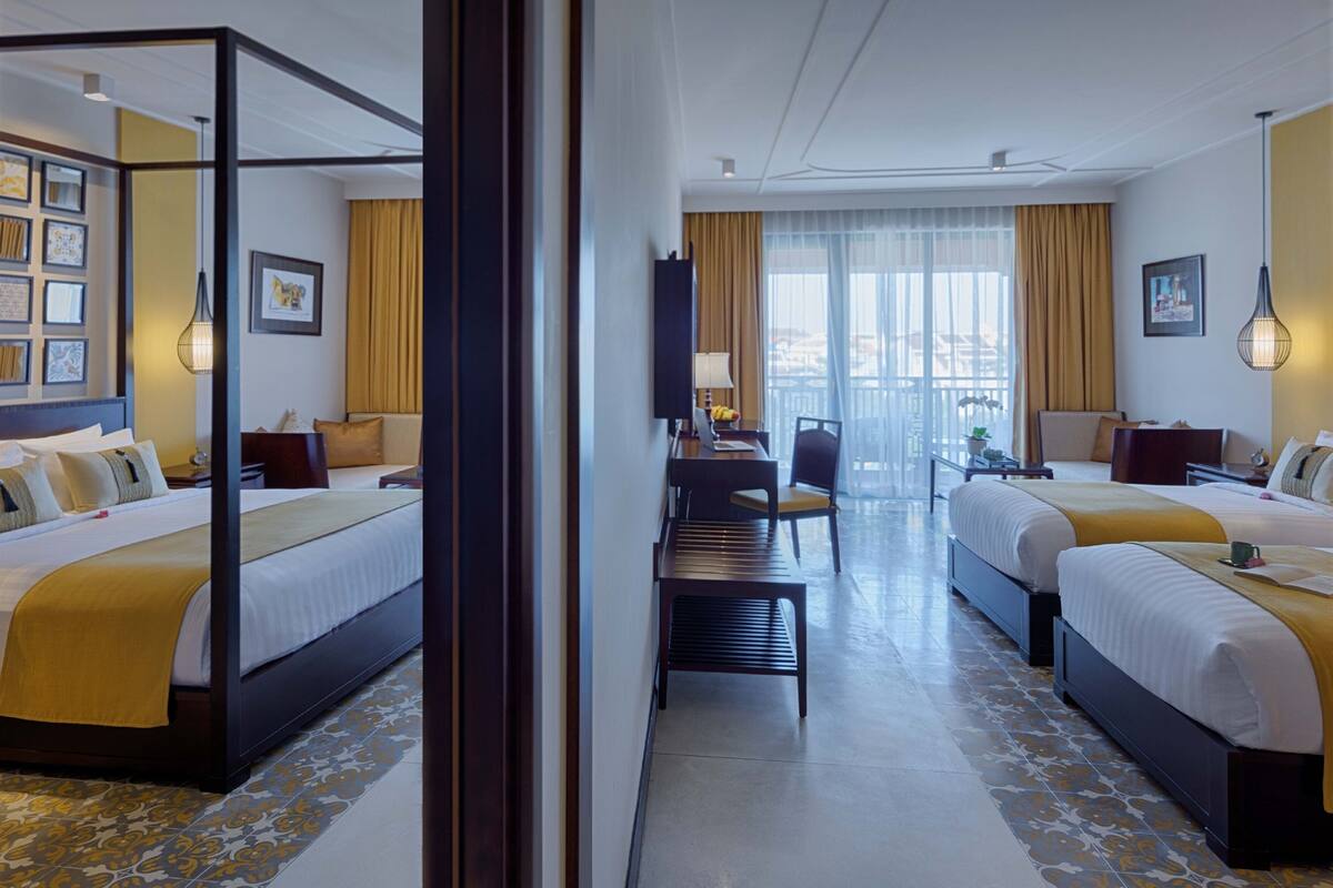 Habitación de hotel con dos camas, un escritorio, una silla y vista a la ciudad.