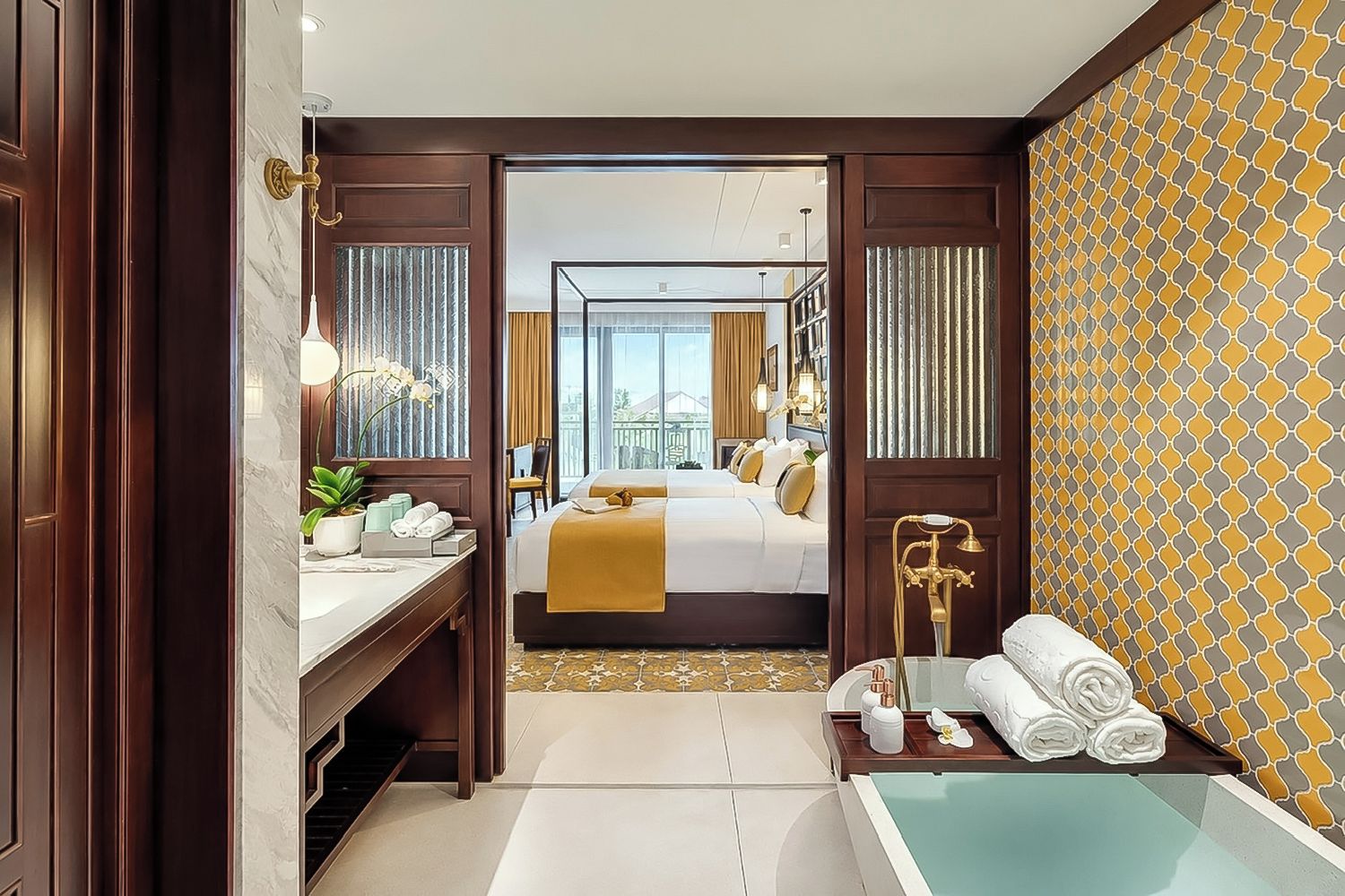 A hotel room with a bed, a bathroom with a bathtub, a vanity with a mirror, and a view of the city.
