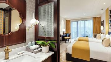 Una habitación de hotel con una cama grande, un escritorio y un baño con espejo y lavamanos.