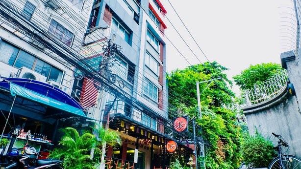 A multi-story building with a restaurant on the ground floor, outdoor seating, and a bicycle parked outside. - The Konnect Hotel (Bangkok)