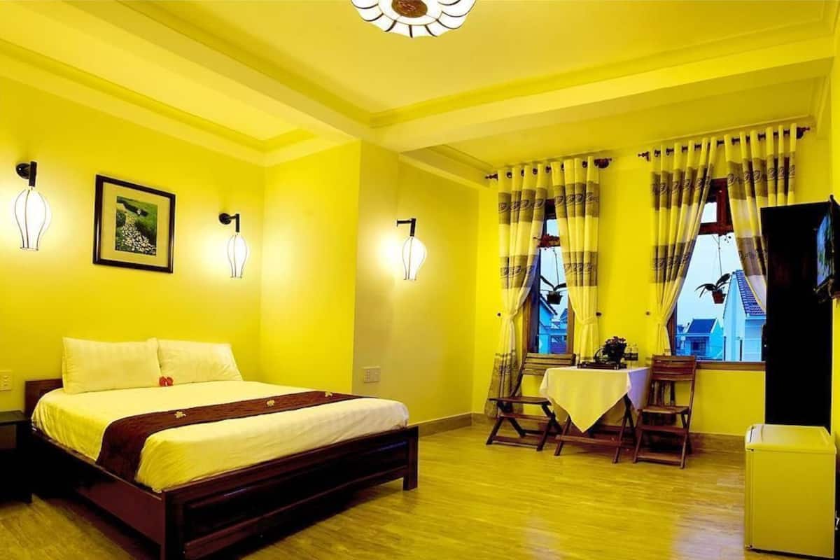 A room with a bed, a table, chairs, and a television.