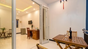 A modern interior with a wooden dining table, a kitchen area, and a sliding glass door leading to an outdoor space. - Horizon Homestay (Da Nang)