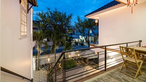 A balcony with a view of a street, a white fence, and a table with chairs. - Horizon Homestay (Da Nang)