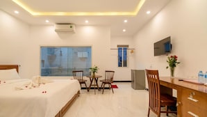 A hotel room with a bed, a desk, a chair, a TV, and a window with a view. - Horizon Homestay (Da Nang)
