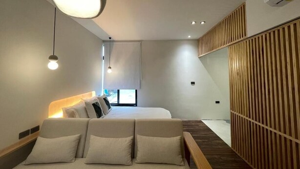 A modern hotel room with a large bed, bedside tables, a wooden partition, and a ceiling light fixture. - Green Inn Kaohsiung (Kaohsiung)