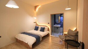 A modern bedroom with a bed, bedside tables, a chair, and a bathroom visible through an open door. - Green Inn Kaohsiung (Kaohsiung)