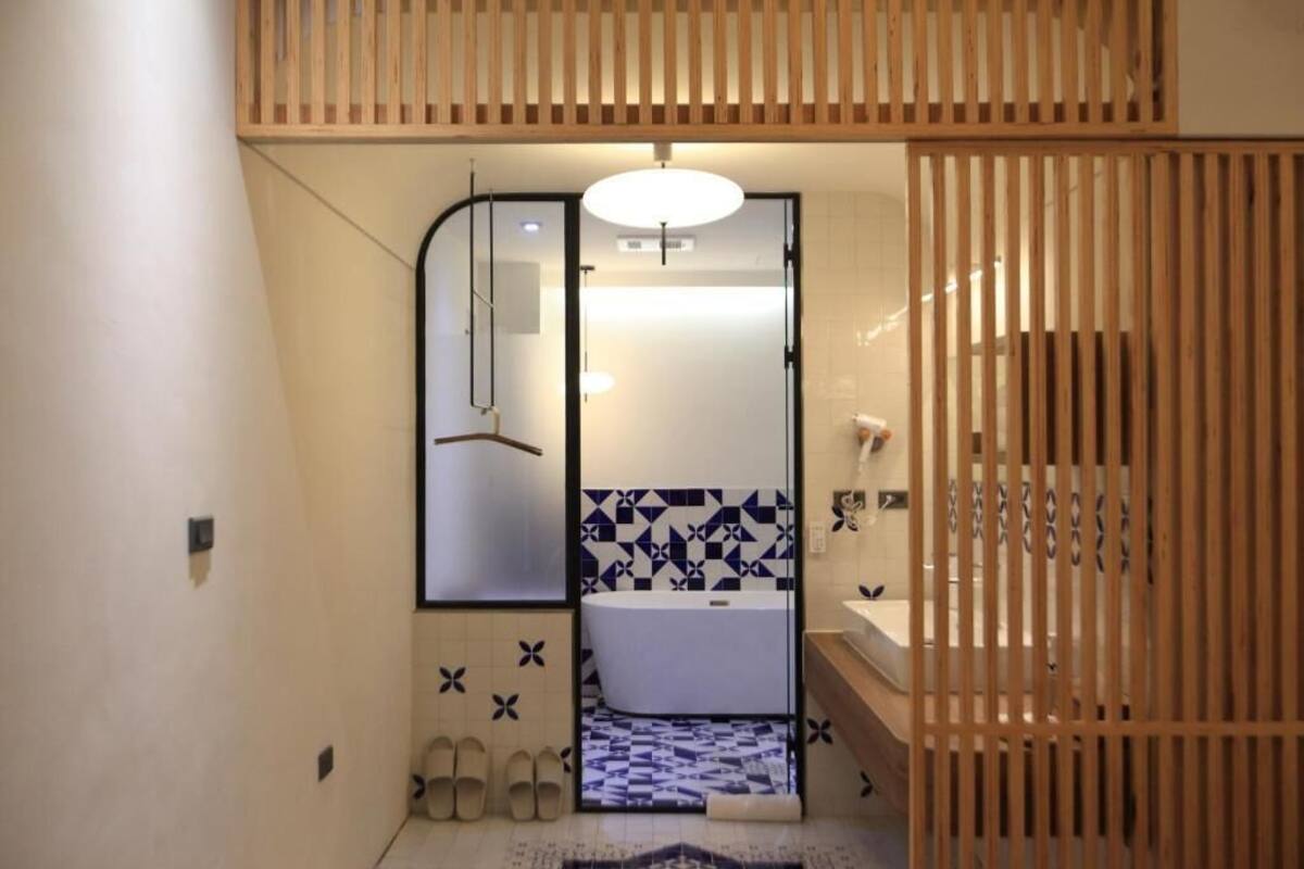 A compact bathroom with a white sink, a mirror, and a patterned tile backsplash.