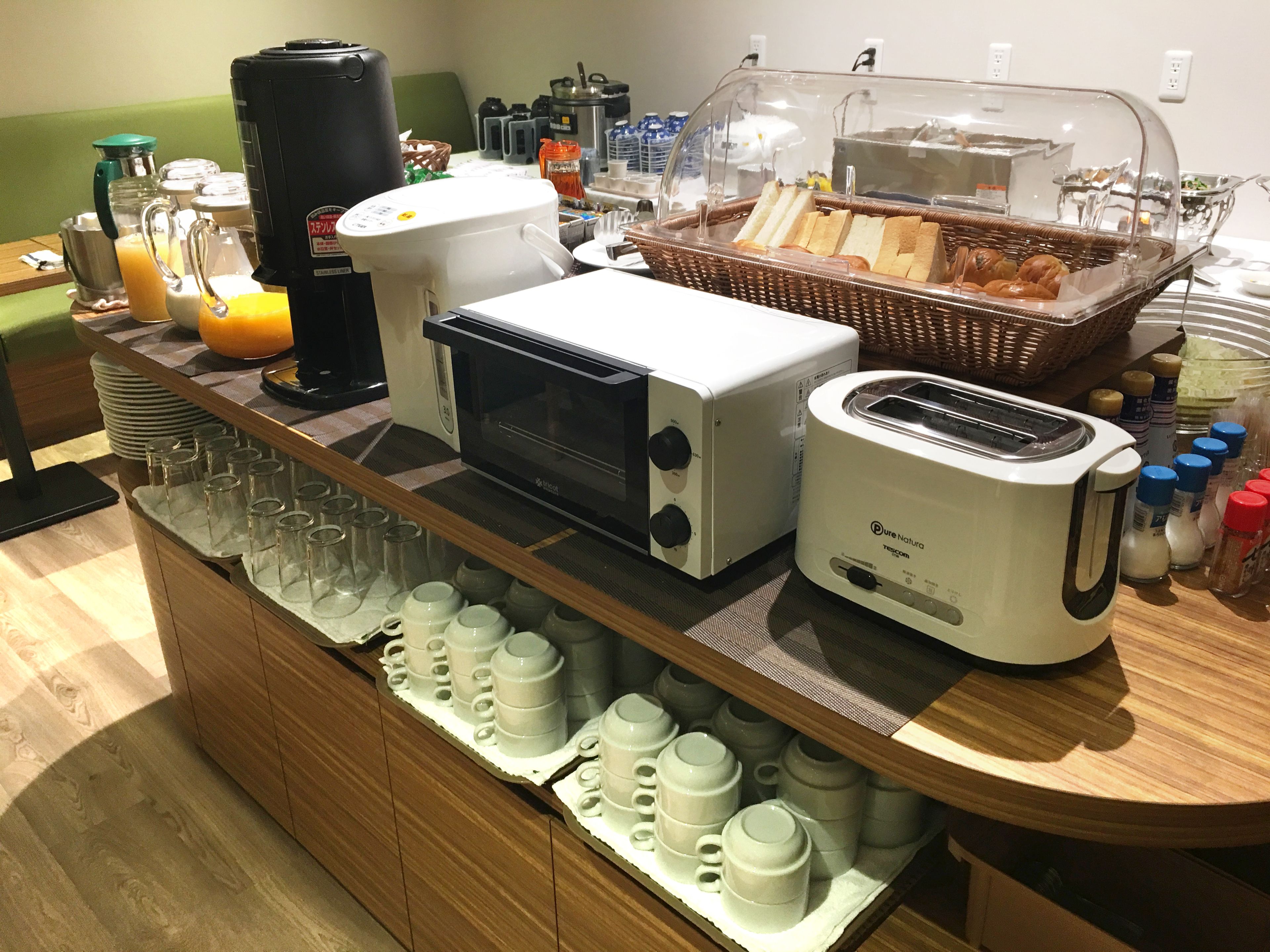A breakfast buffet setup with a coffee maker, toaster, and bread basket.