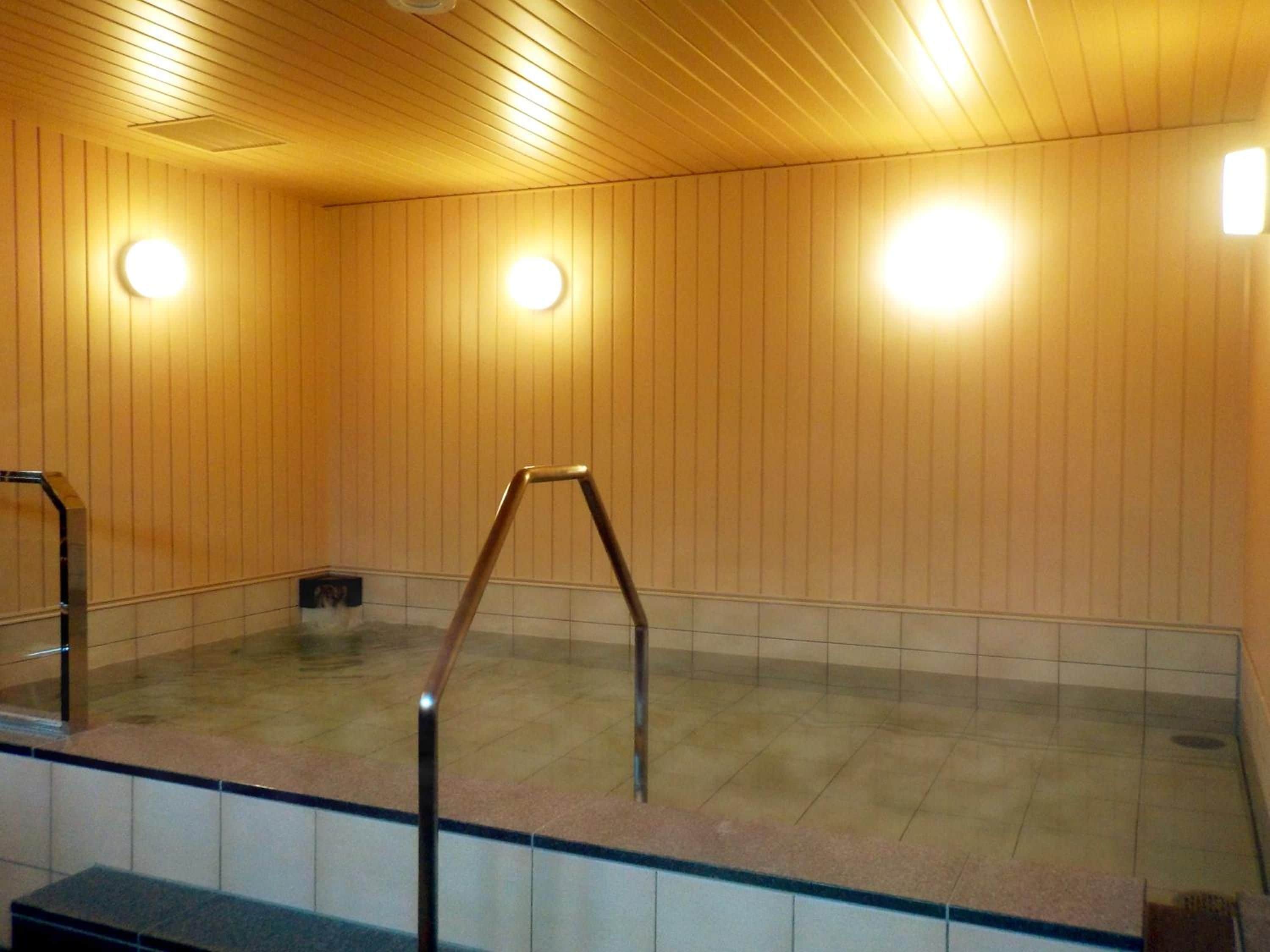 A hot tub area with wooden panel walls, tiled flooring, and a metal ladder.