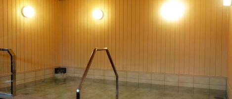 A hot tub area with wooden panel walls, tiled flooring, and a metal ladder.