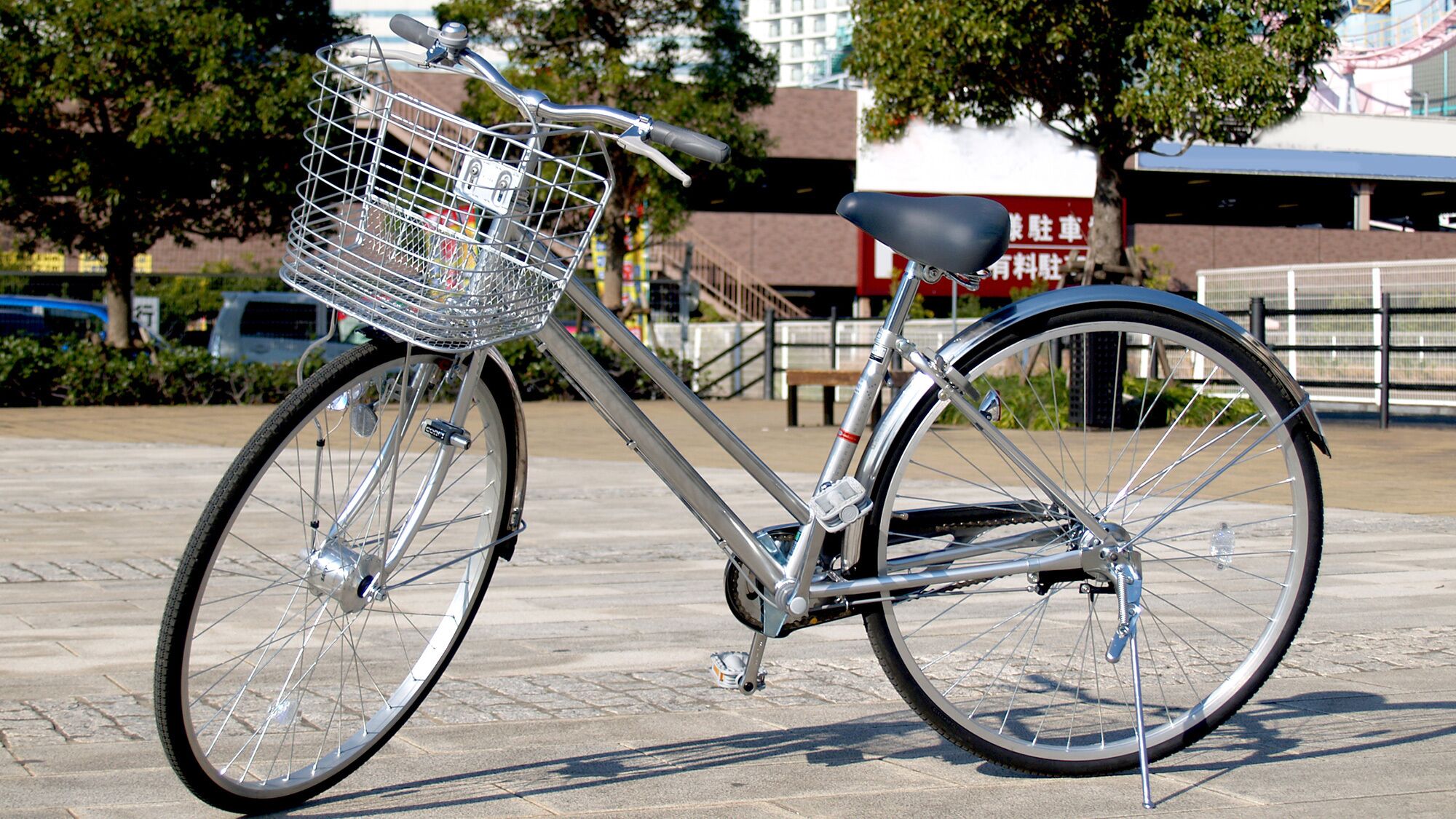 Una bicicleta estática con una cesta delantera, estacionada sobre una superficie pavimentada.