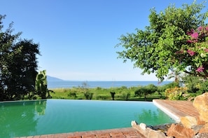 Una piscina al aire libre, una piscina con borde infinito, sombrillas