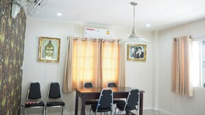 A dining area with a table, chairs, ceiling fan, air conditioning unit, and two framed pictures on the walls. - Baan Tukta at Beach (Cha-am)
