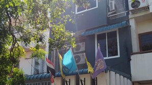 A building with multiple windows, a blue gate, and flags hanging on a line. - Baan Tukta at Beach (Cha-am)