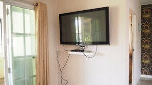 A room with a TV mounted on the wall, a sliding glass door, and patterned wallpaper. - Baan Tukta at Beach (Cha-am)