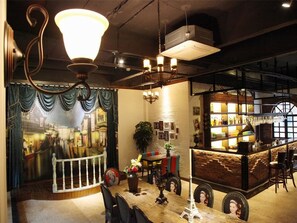 Un restaurant acollidor amb una decoració antiga, que destaca un mural, una zona de bar i un espai d'esmorzar amb un penjador.