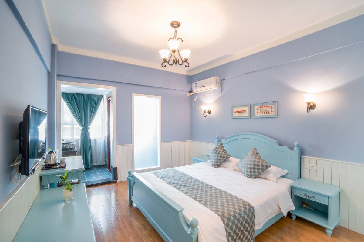 A bedroom with a bed, bedside table, lamp, and a television.