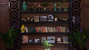 A dining area with a round table surrounded by colorful chairs, a bookshelf with various items, and potted plants. - Memory Inn Guilin Central (Guilin)
