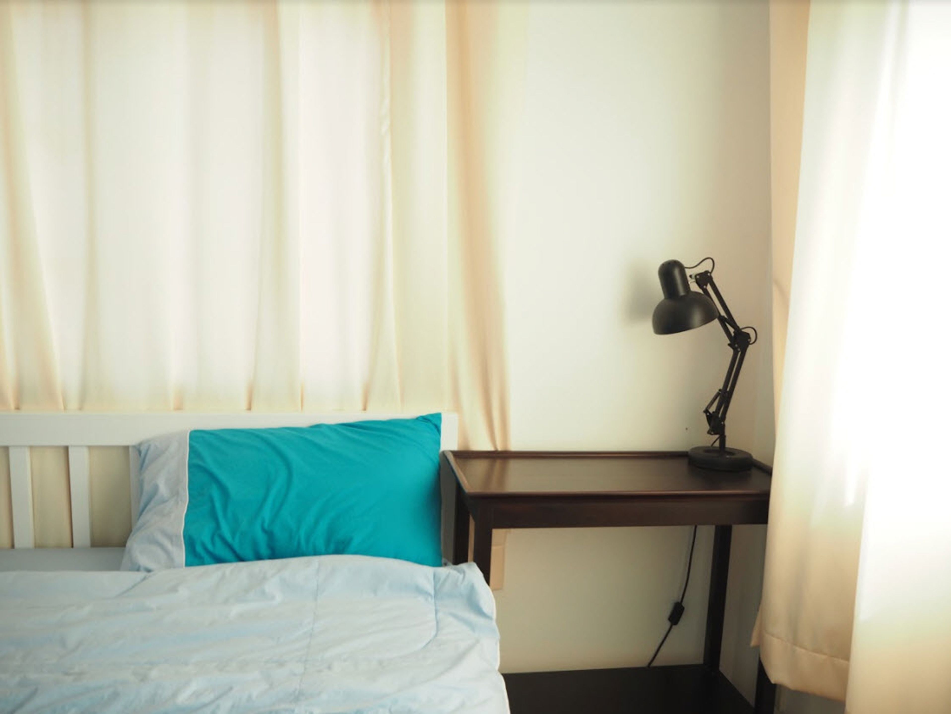 A hotel room with a bed, a desk, and a lamp.