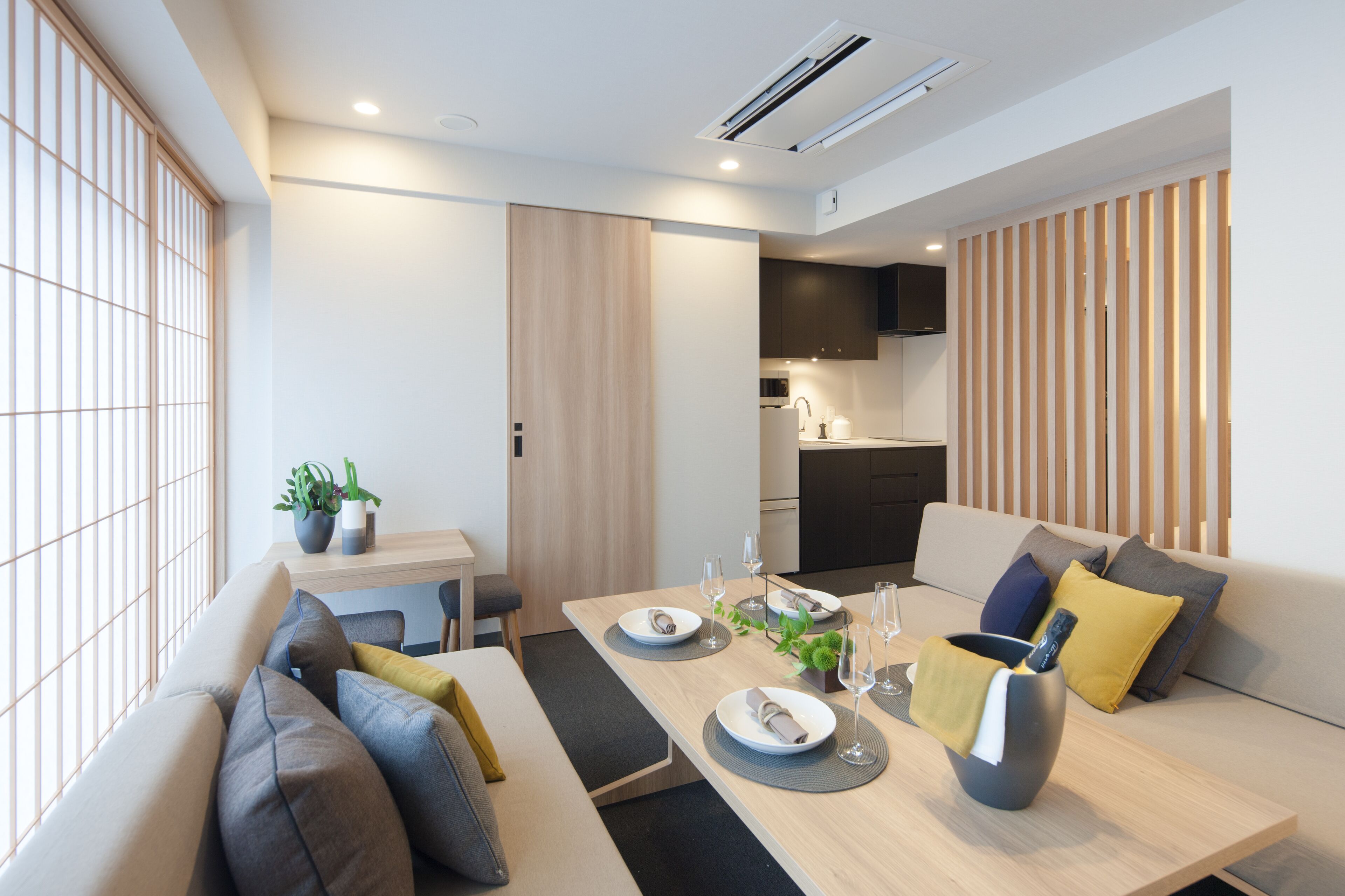 A modern living room with a sofa, dining table, and kitchen area.
