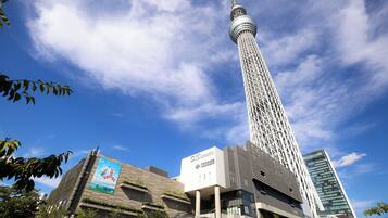 A tall tower with a spherical observation deck, surrounded by modern buildings and greenery.