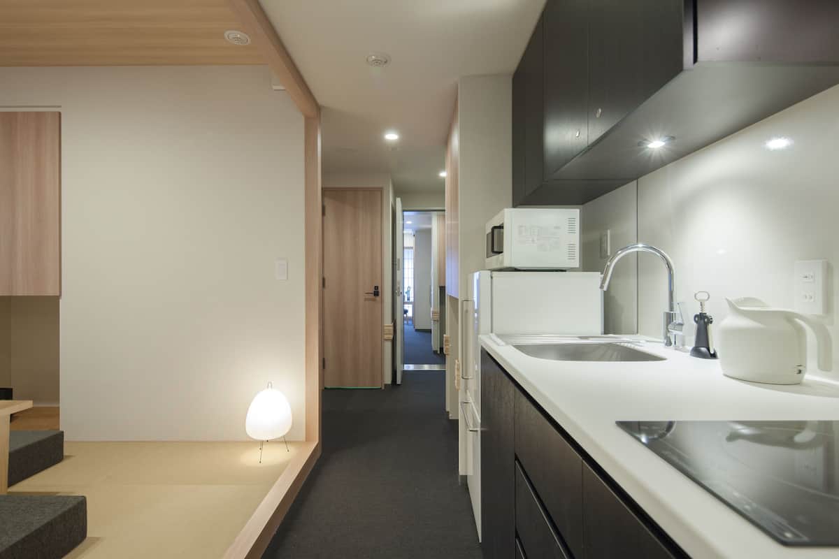 A modern kitchen with a white countertop, stainless steel sink, and a microwave.