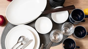 A neatly arranged dining table with plates, bowls, chopsticks, and cutlery.