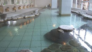 A traditional Japanese onsen with stone baths, a tiled floor, and a row of sinks with mirrors and soap dispensers. - Yunominesou (Tanabe)
