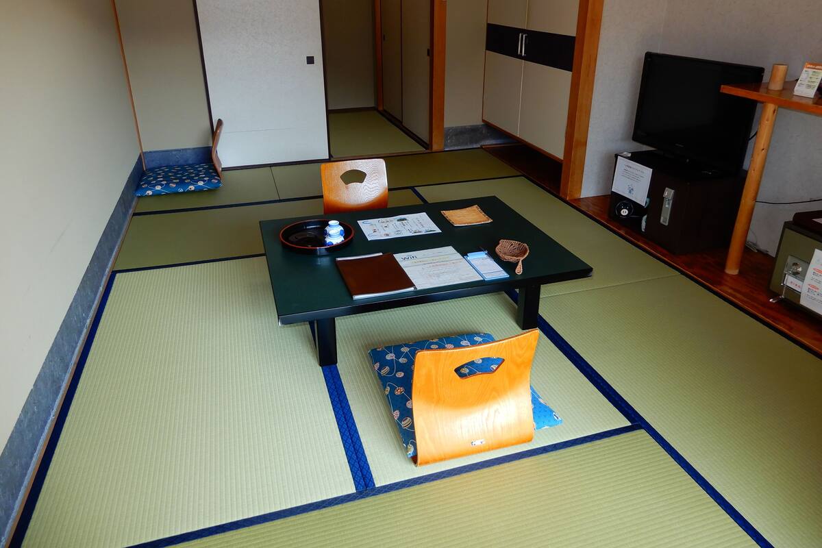 A traditional Japanese room with tatami flooring, a low table with a water bottle, a notebook, and a small bag.