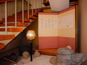A traditional Japanese room with tatami flooring, a shoji screen, and a wooden staircase.