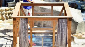 A wooden structure with Japanese text on its sides, possibly a traditional Japanese building or shrine. - Yunominesou (Tanabe)