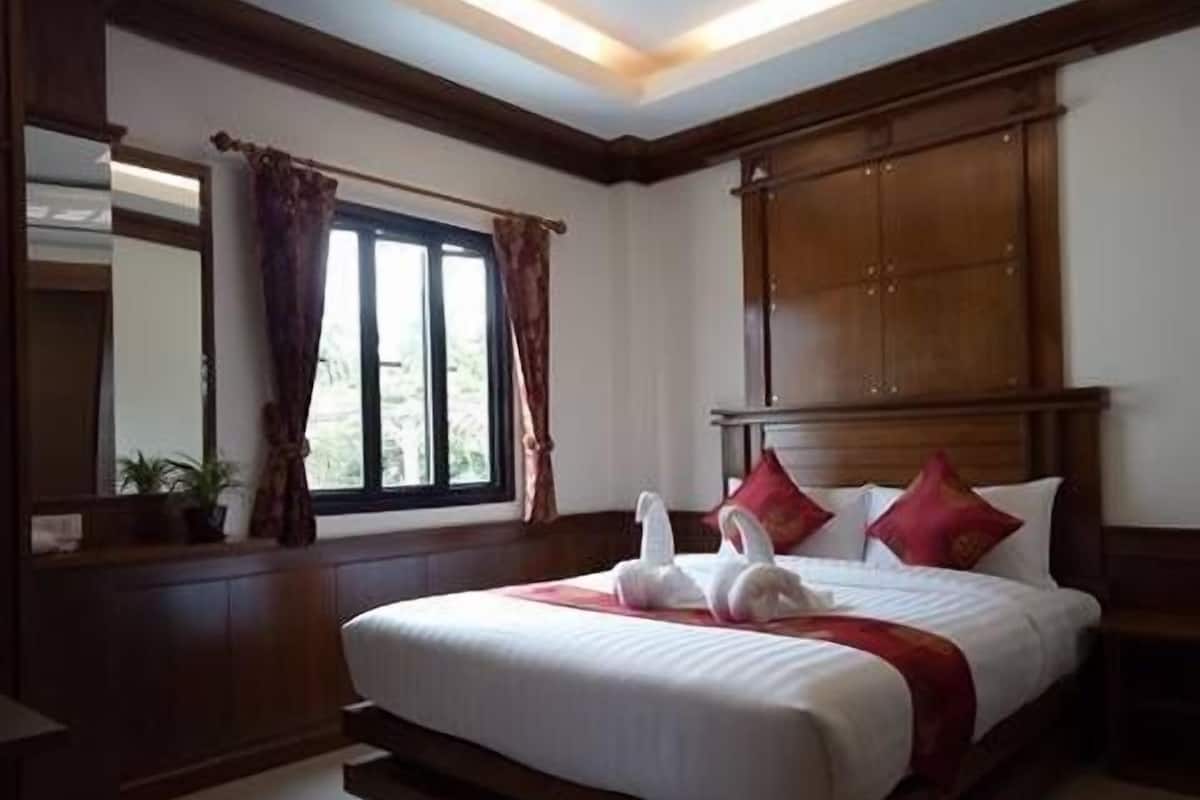 Une chambre d’hôtel avec un grand lit, une tête de lit en bois et une fenêtre avec des rideaux.