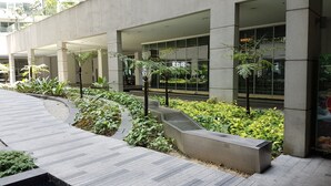 A modern building with large windows, a landscaped garden with various plants, and a paved walkway. - Regalia Studio 109 Suites (Kuala Lumpur)