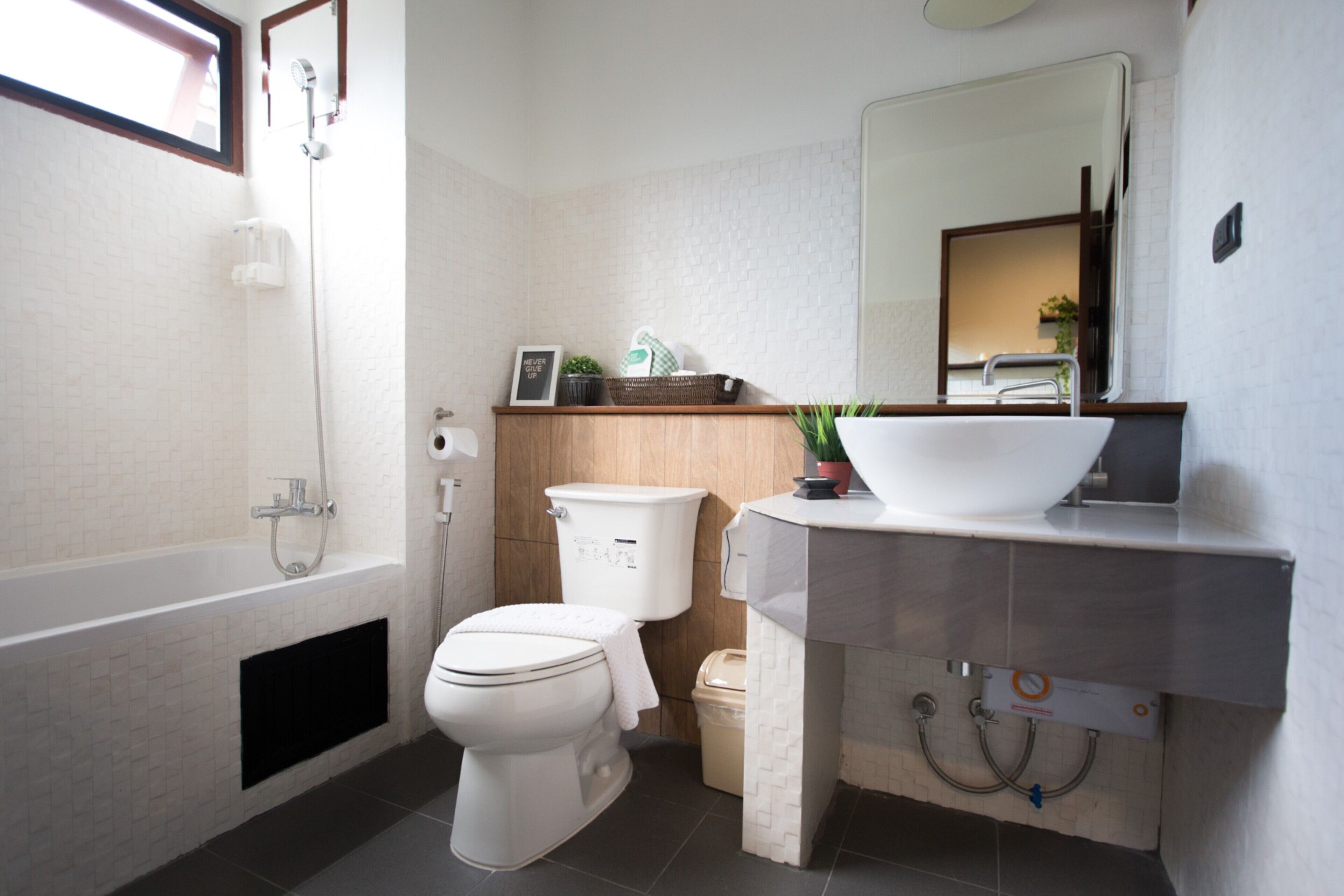 Ein modernes Badezimmer mit Badewanne, Toilette, Waschbecken und Spiegel.