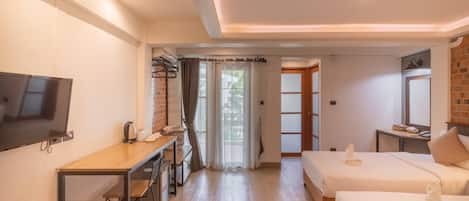 Une chambre d’hôtel équipée d’une télévision, d’un bureau avec une chaise, de deux lits, d’une petite table et d’une fenêtre avec des rideaux.