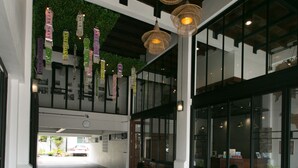 Un vaste couloir doté d’un haut plafond, de grandes fenêtres et de lampes en osier suspendues.