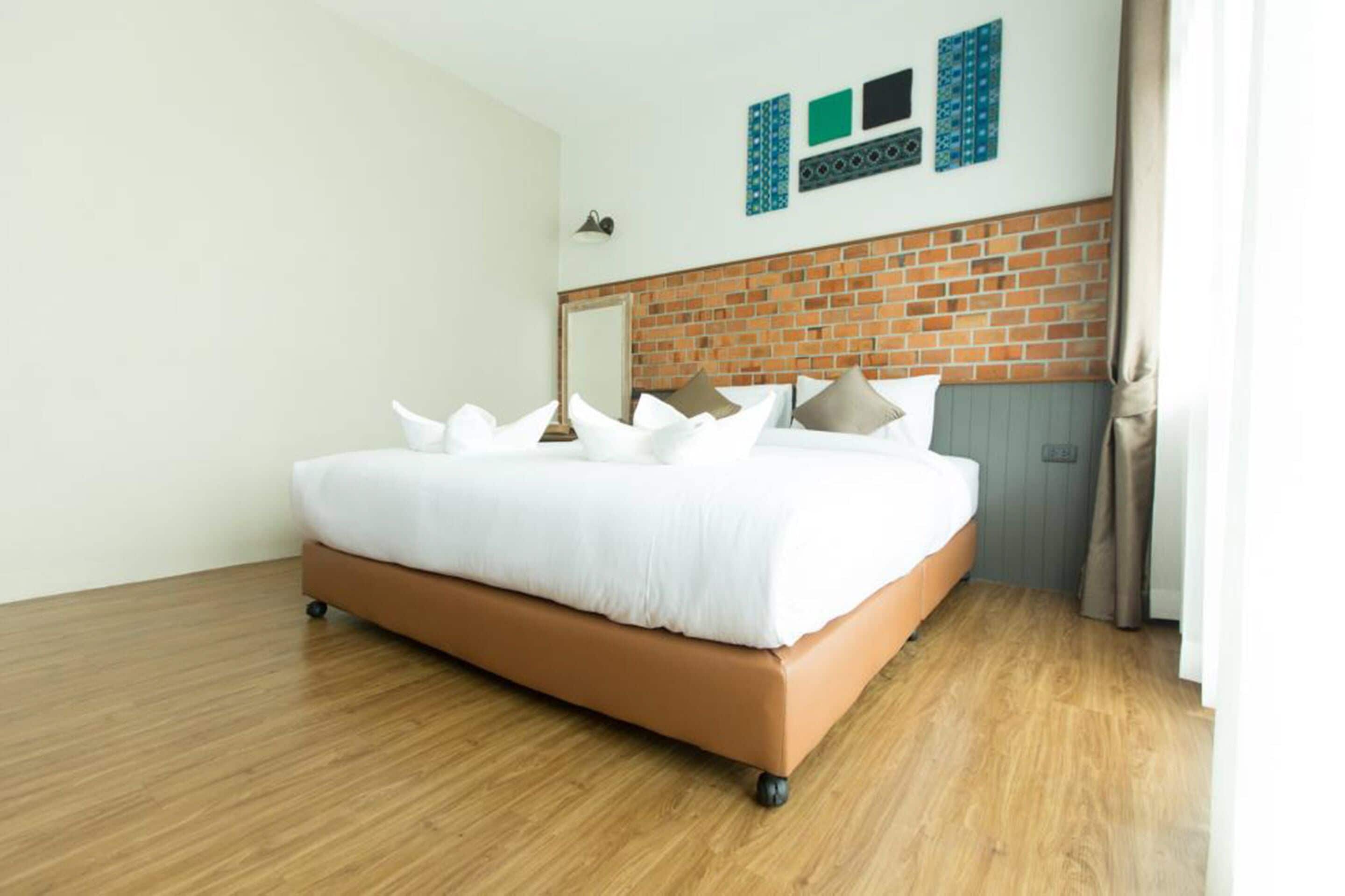 Une chambre d’hôtel moderne avec un grand lit, un mur décoratif en briques et un plancher en bois.