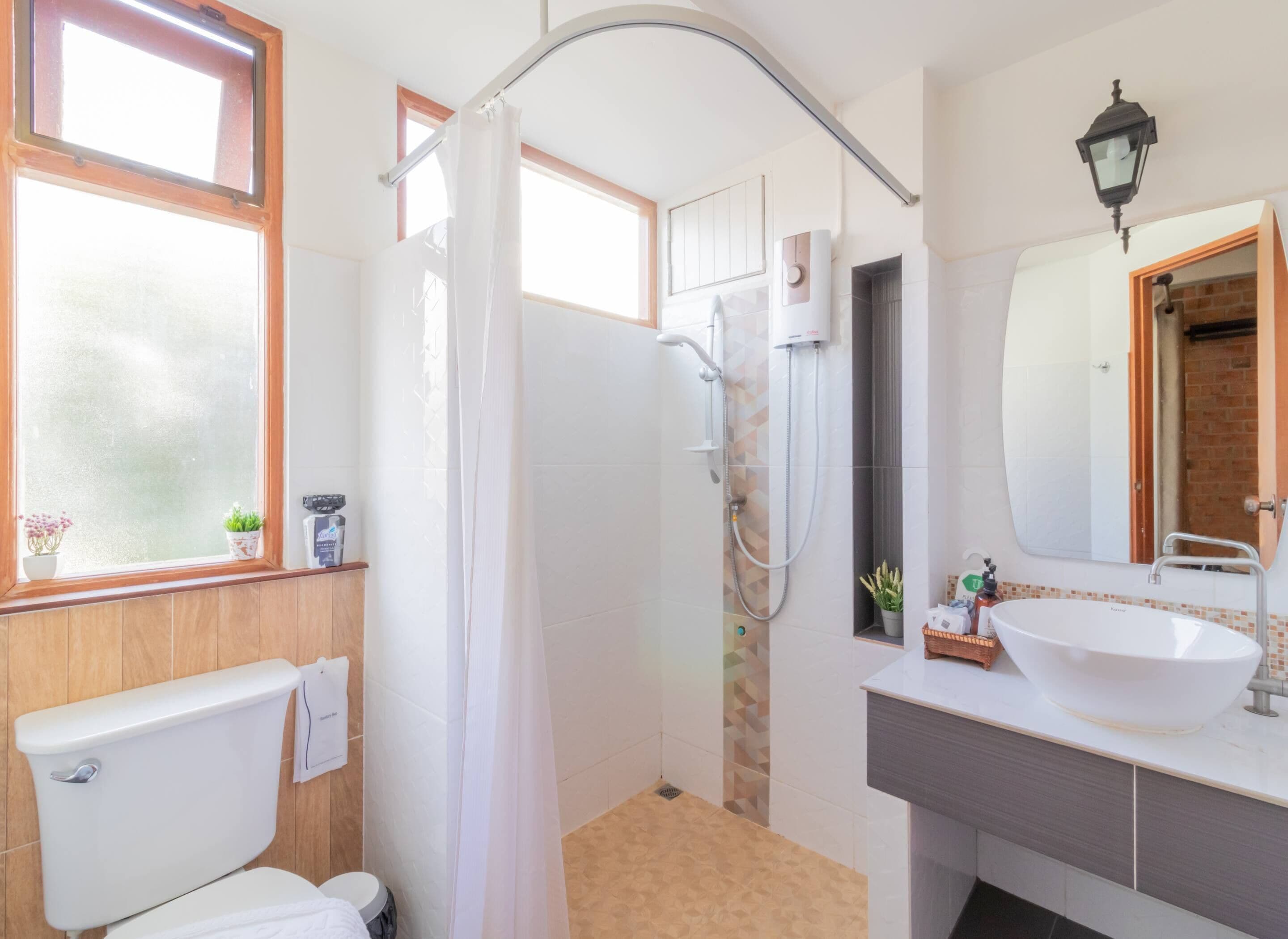 Ein Badezimmer mit Toilette, Dusche, Waschbecken und einem Fenster.
