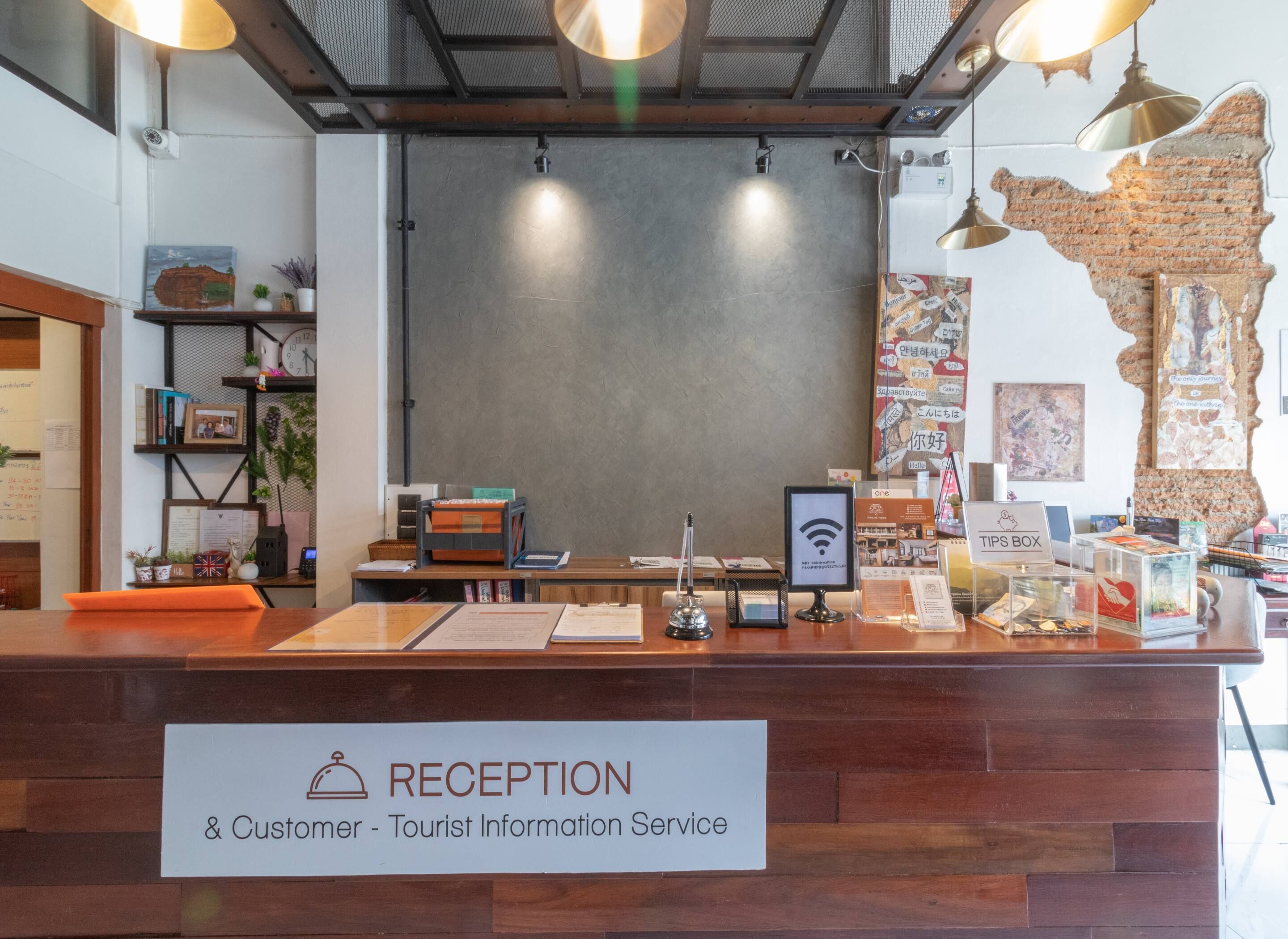 A reception desk with a sign reading "RECEPTION & Customer - Tourist Information Service". There are various informational brochures and a Wi-Fi symbol on the desk.