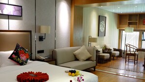 A hotel room with a bed, a bedside table, a nightstand, a sofa, a dining table with fruit and wine, and a view of the outdoor area. - Chengdu E Hotel (Chengdu)
