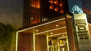 A modern building with vertical wooden slats and illuminated windows at night. - Chengdu E Hotel (Chengdu)