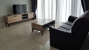 Un salon moderne avec un canapé foncé, une table basse en bois et un téléviseur posé sur un meuble en bois.