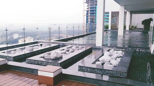 Un espace piscine aménagé sur le toit, doté de plusieurs éléments aquatiques et offrant une vue sur le paysage urbain.