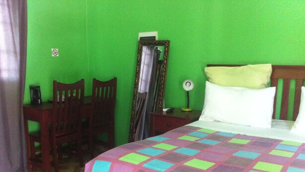 A room with a bed, a desk, and chairs. - Gomwe Guest Inn (Nata)