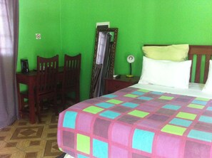 Una habitación con una cama, un escritorio y sillas.