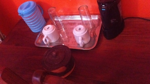 A tray with two white teapots and a blue water bottle on a wooden table.