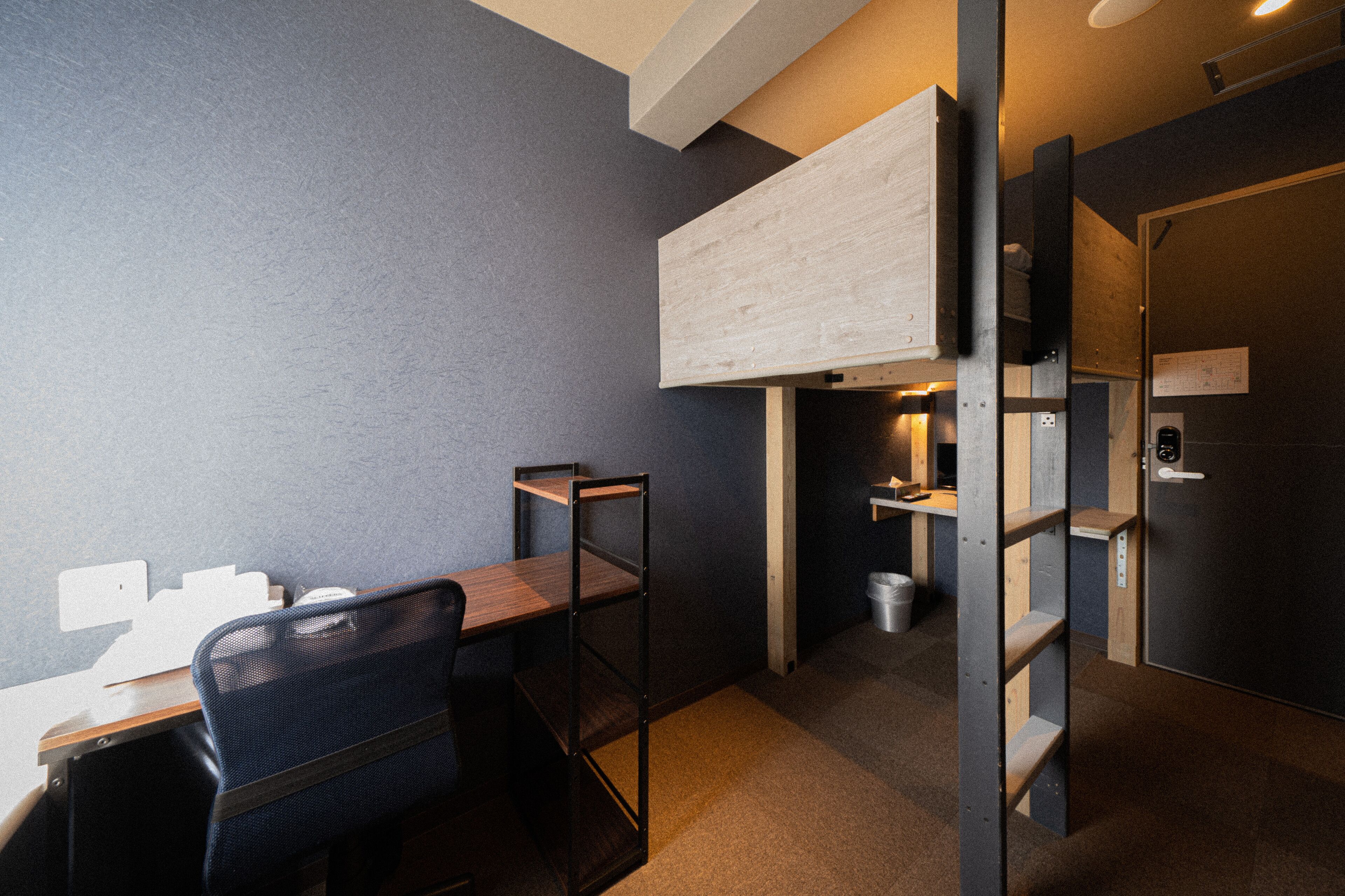 A compact office space with a desk, chair, and shelving units against a grey wall.