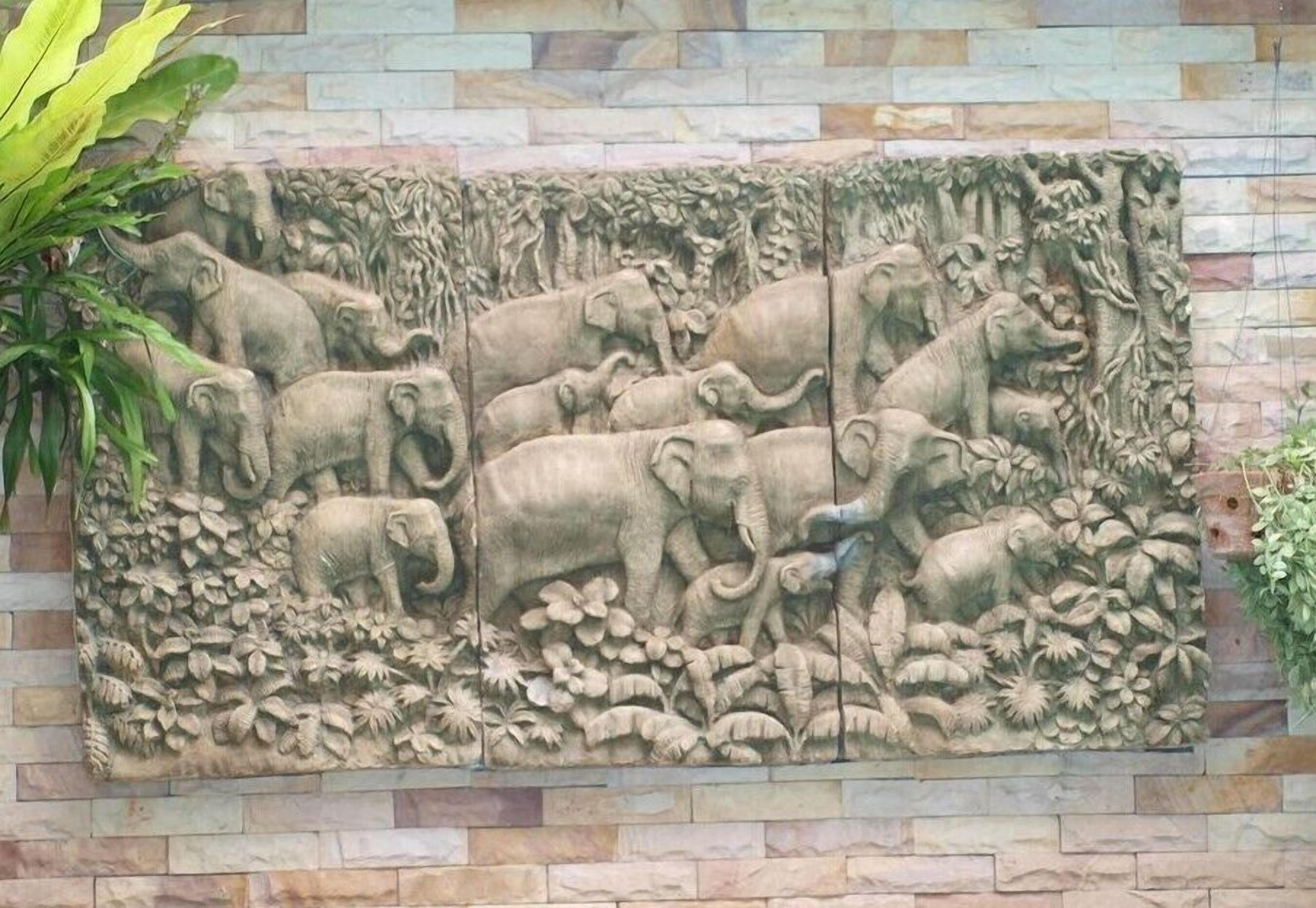A stone wall with a relief sculpture of elephants and foliage.