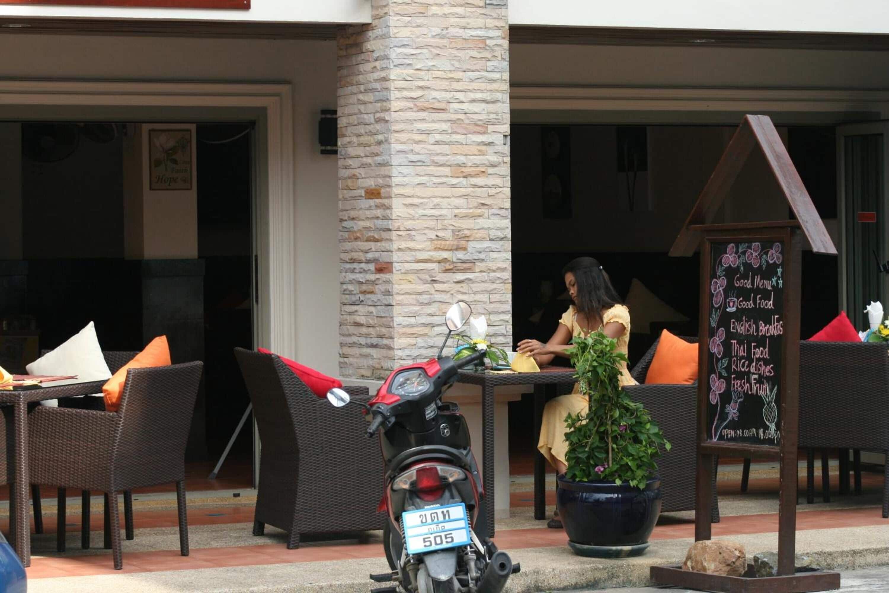 An outdoor seating area with wicker furniture, a scooter, and a chalkboard menu.