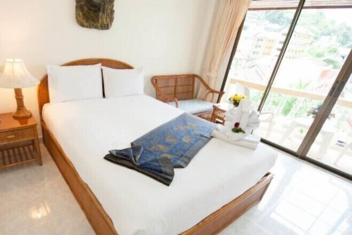 Una cama bien hecha con una toalla azul y un pequeño arreglo floral.